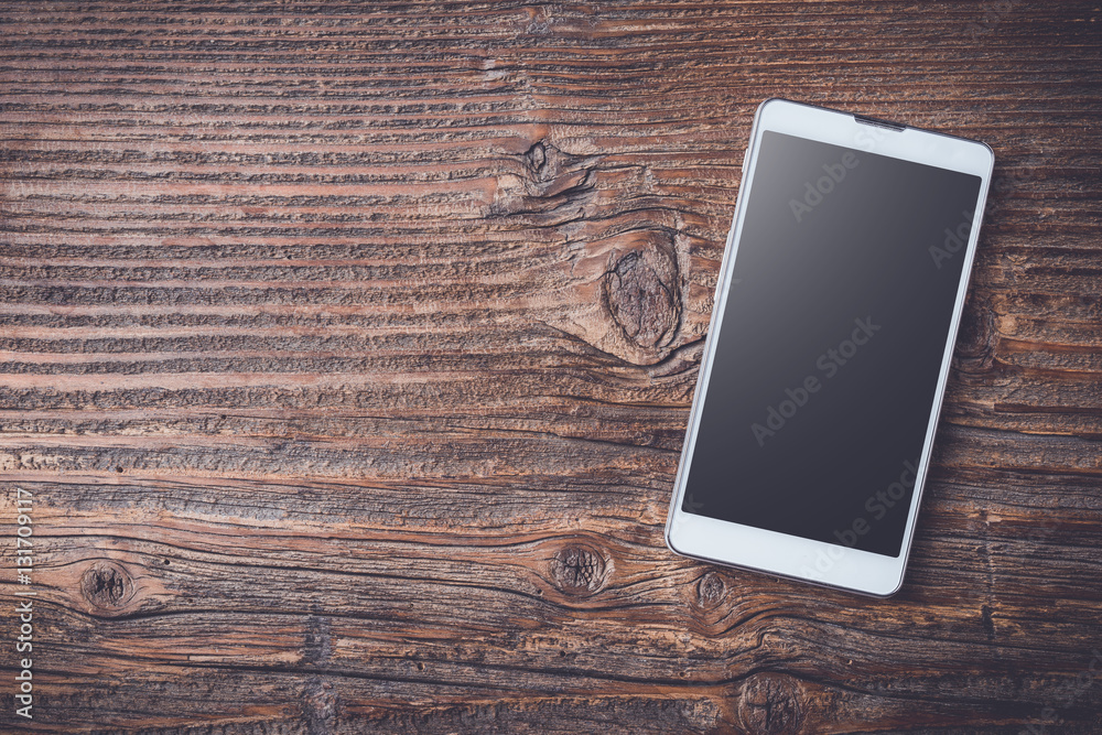 White smart phone on an old wooden table White smart phone on an old wooden table