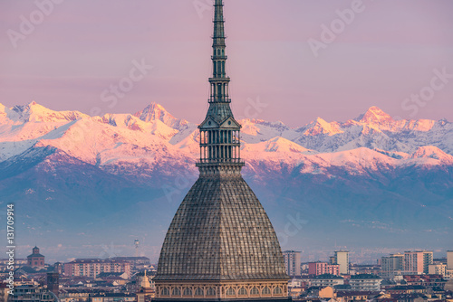 Torino (Turin, Italy): cityscape at sunrise with details of the Mole Antonelliana towering over the city. Scenic colorful light on the snowcapped Alps in the background.