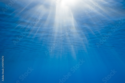 Sunbeams penetrating blue ocean background.
