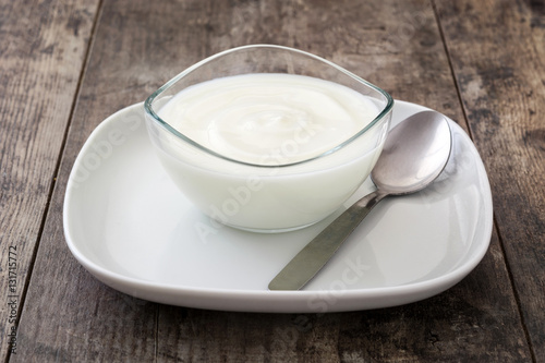 Greek yogurt in glass bowl on wooden table
