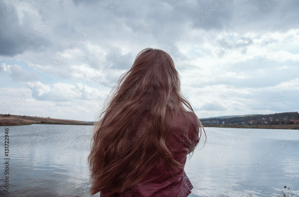 Beautiful girl with long hair admire the lake