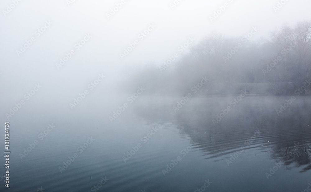 Fototapeta premium Mist hovering over a cold lake in Goldsworth Park, Surrey, Wokin
