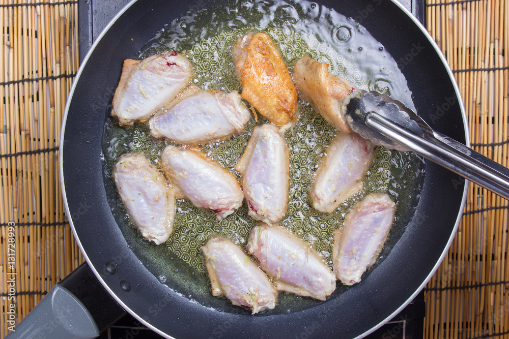 Chef frying chicken wings in pan Chef frying chicken wings in pan