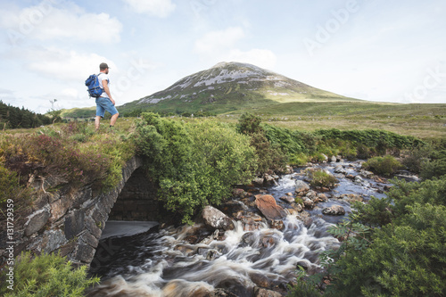 Lone walker stood on an old bridge in the poisoned Glen with a v photo