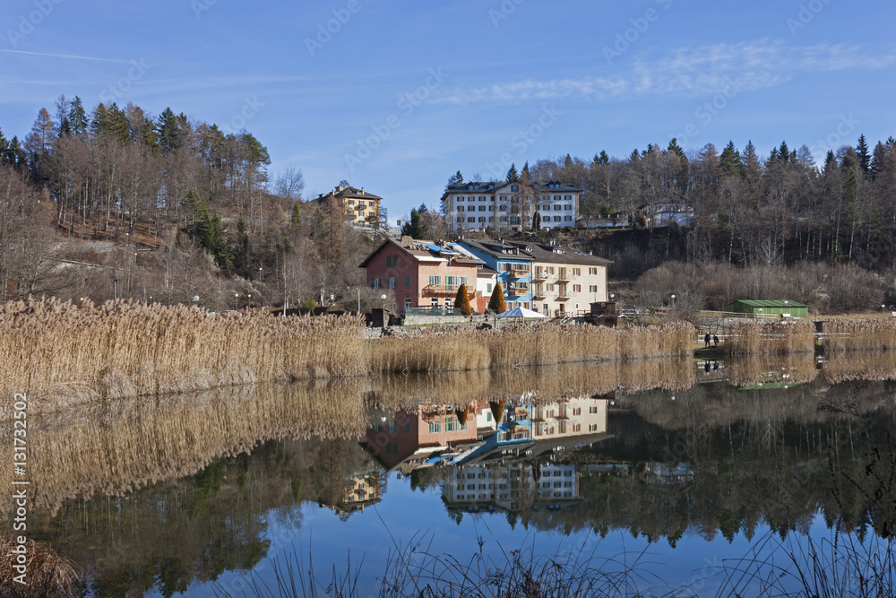 Reflected in blue waters of Lavarone Lake, on the Alpe Cimbra