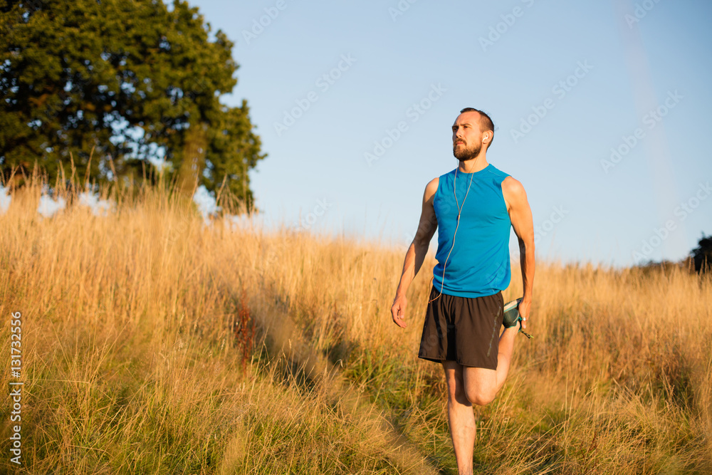 Young athletic man taking a post run break at sunset in the park