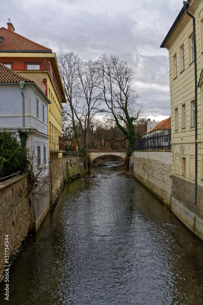 A narrow channel of river going from in between a row of buildings in Prague