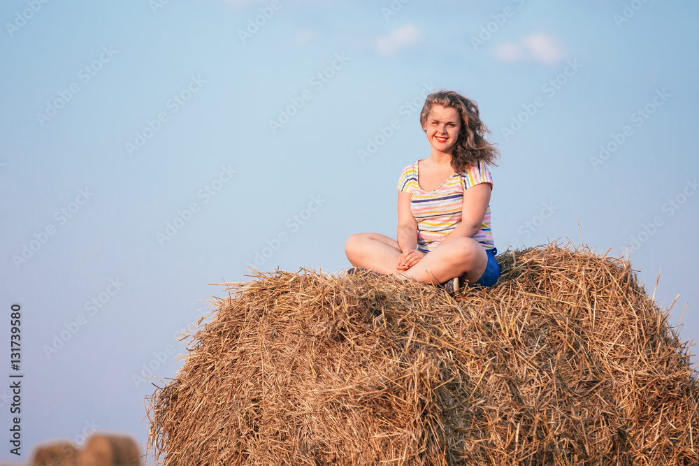 Beautiful Plus Size Young Woman In Shirt Sit Near Hay Bales In Summer Beautiful Plus Size Young Woman In Shirt Sit Near Hay Bales In Summer