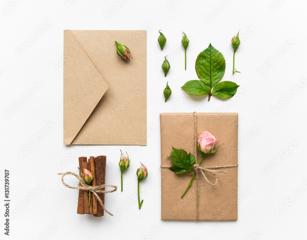 Gift box and envelope in eco paper on white background. Presents decorated with roses. Holiday concept, top view, flat lay Gift box and envelope in eco paper on white background. Presents decorated with roses. Holiday concept, top view, flat lay