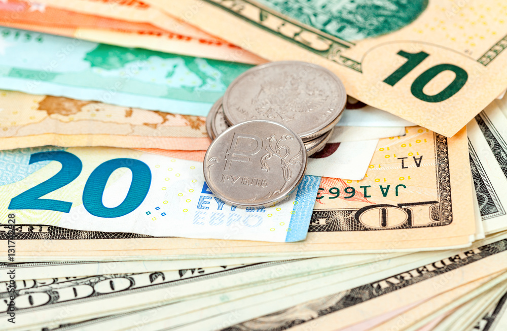 Russian rubles coins over different currency banknotes close up Russian rubles coins over different currency banknotes close up