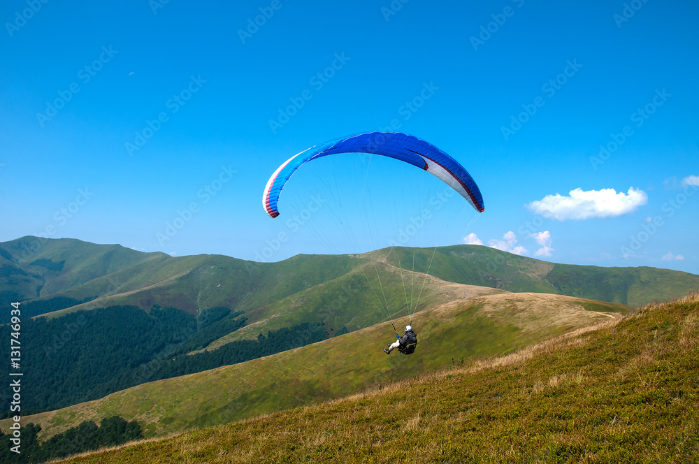 Paraglider flies paraglider over the tops of the mountains in summer sunny day. Karpaty, Ukraine Paraglider flies paraglider over the tops of the mountains in summer sunny day. Karpaty, Ukraine