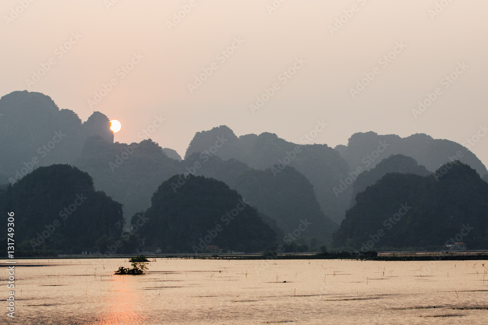Asian fishing boats at sunset on a background of mountains.