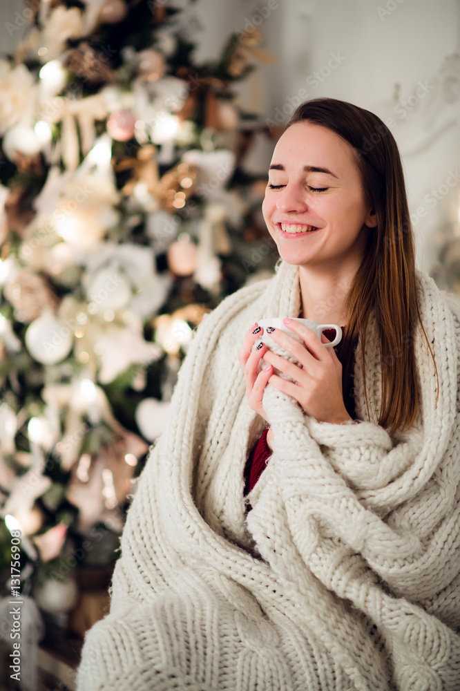 Happy young woman with cup of hot beverage near christmas tree Happy young woman with cup of hot beverage near christmas tree