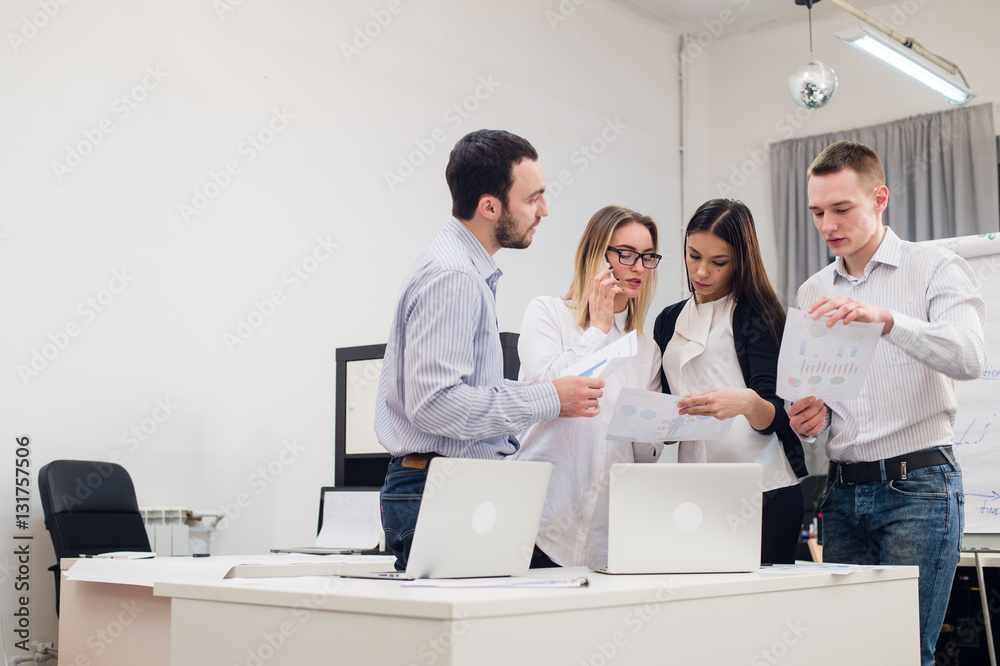 Group of four diverse men and women in casual clothing talking in office Group of four diverse men and women in casual clothing talking in office