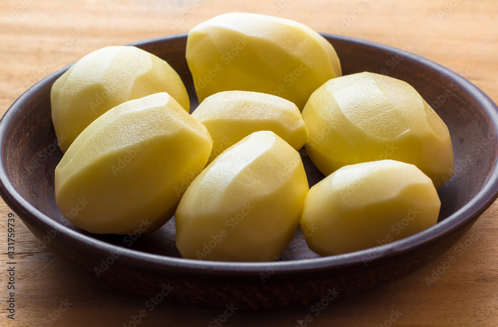 Seven large fresh peeled potatoes in the dish. Close-up