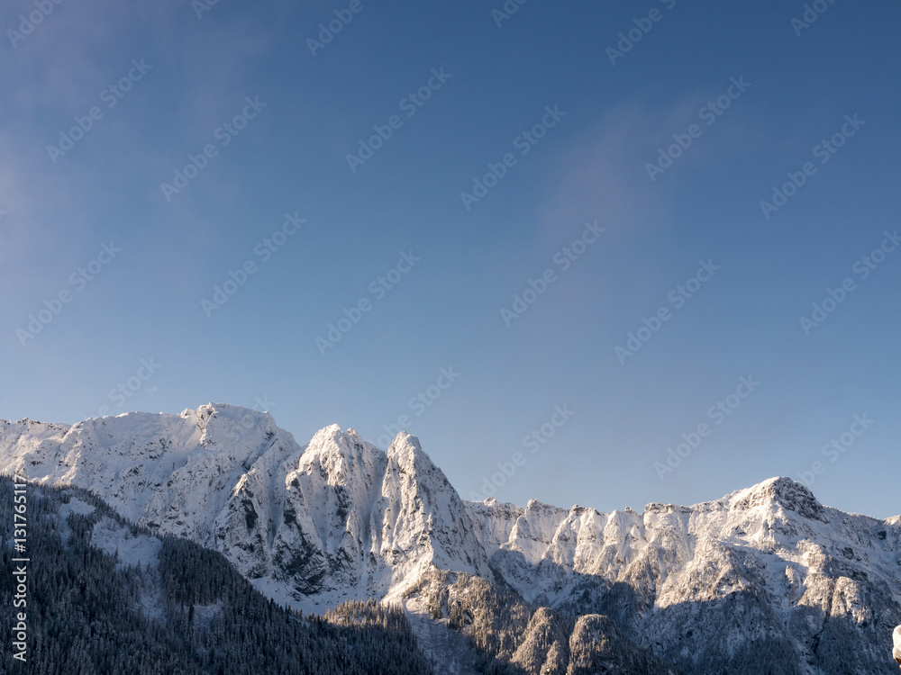 Blue Sky Nature Background Above Snow Covered Jagged Peaks on Mountain Ridge