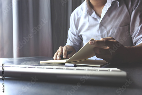 businessman reading a book and writing notes on wooden table with film colors tone, soft-focus in the background. over light © memorystockphoto