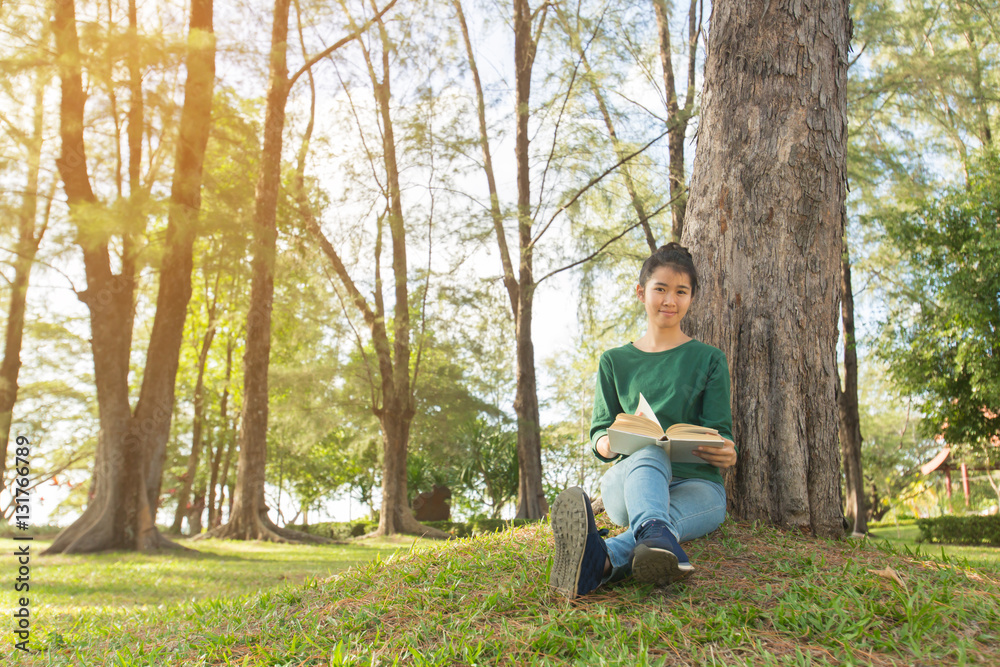 Beautiful young asian woman sitting and reading book in a park Beautiful young asian woman sitting and reading book in a park