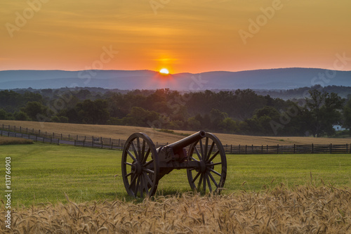 Sun rising behind artillery near a wheat field at Antietam Natio