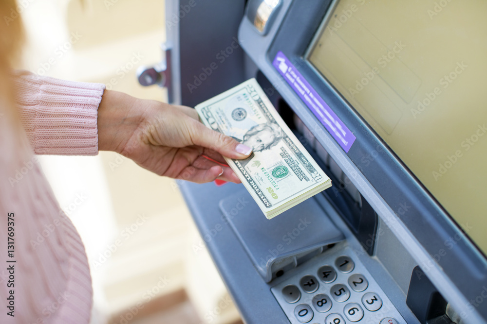 Woman hand withdrawing money from outdoor bank ATM Woman hand withdrawing money from outdoor bank ATM
