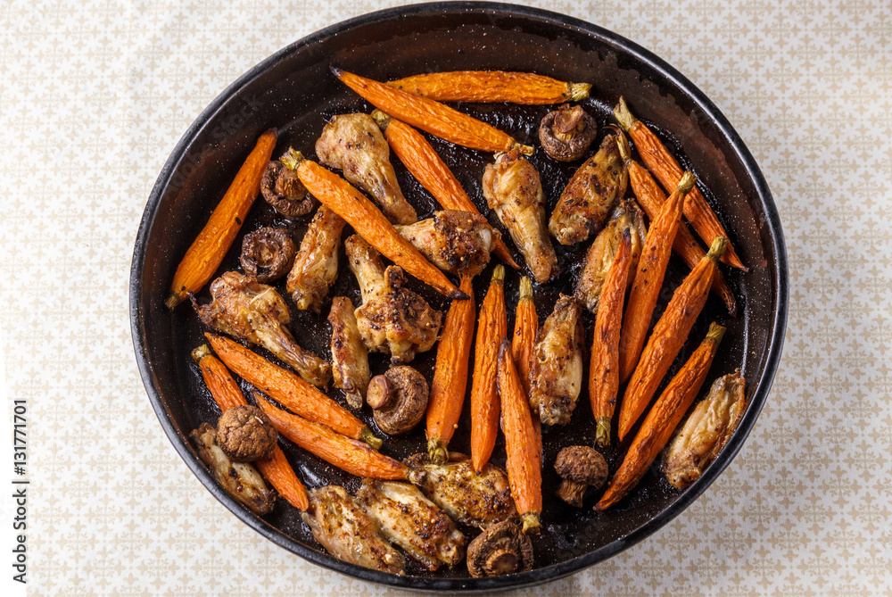 Roasted chicken wings with carrot and mushrooms on a tray Roasted chicken wings with carrot and mushrooms on a tray