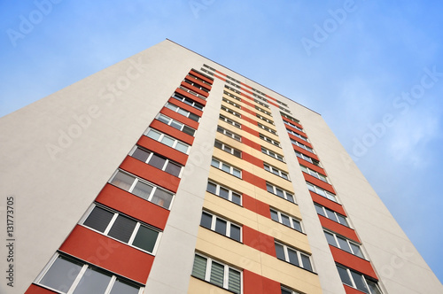  White facade of a modern multistory highrise residential building with red, yellow inserts. Look up.