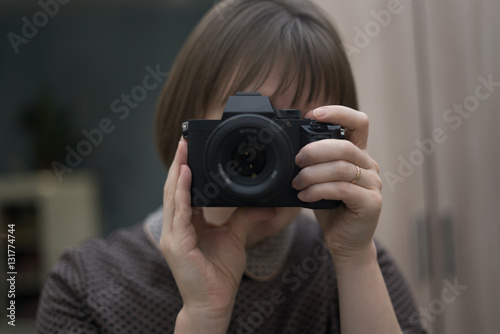 A woman holds a camera and takes pictures of herself in the mirror