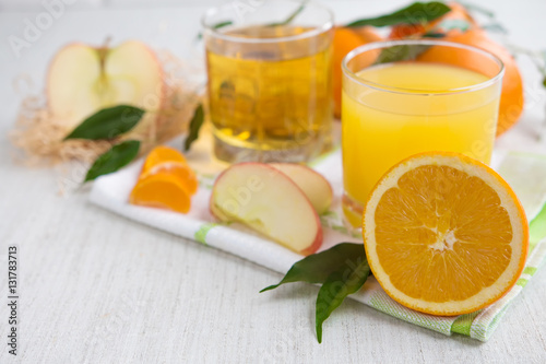 Oranges, apples and fresh juice on a light background