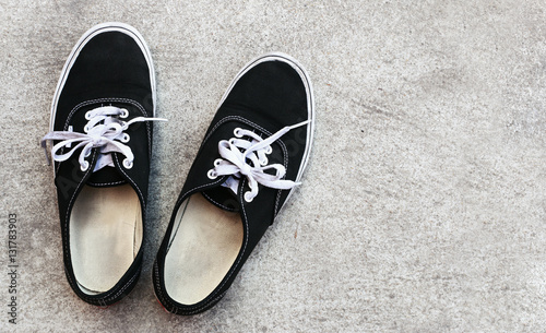 Top view of a pair of black sneakers shoes on concrete floor background.