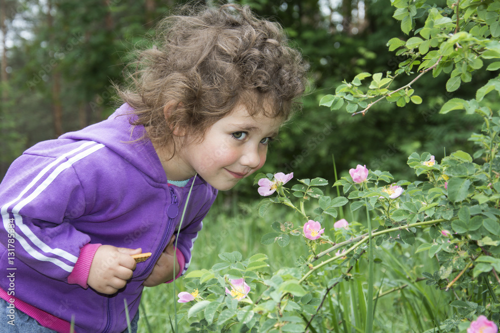 Spring in the forest a little curly-haired girl sniffs a flower Spring in the forest a little curly-haired girl sniffs a flower