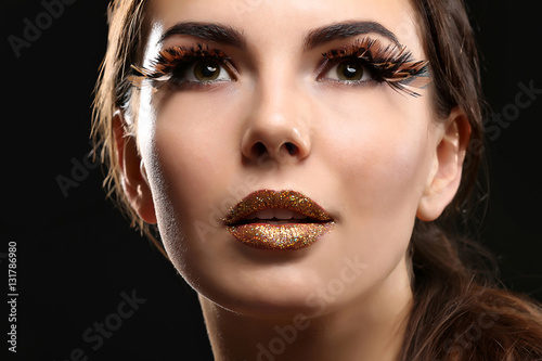 Portrait of beautiful young woman model with bright makeup on dark background
