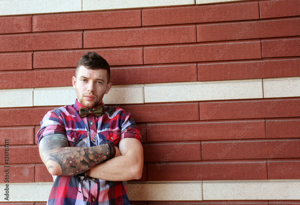 Obraz premium Young tattooed man posing on brick wall background