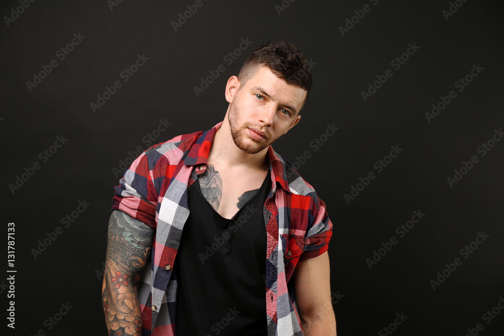 Young tattooed man posing on dark background Young tattooed man posing on dark background