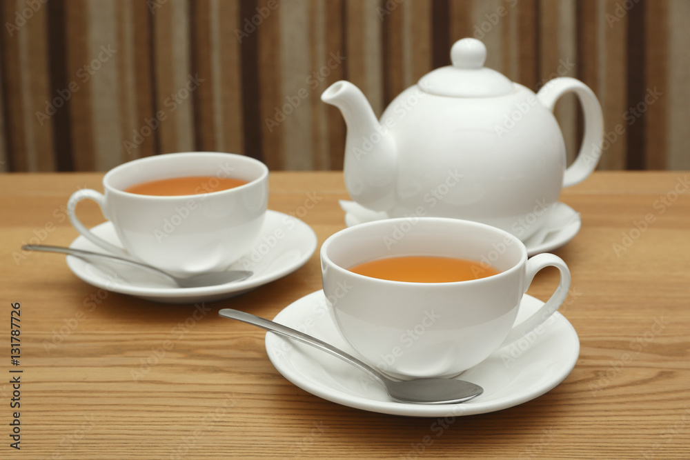 Two cups of hot tea and teapot on wooden table Two cups of hot tea and teapot on wooden table