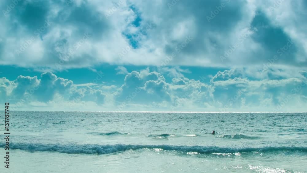 Man Swimming Alone in a Vast Ocean in the Bermuda Triangle in Front of a Majestic Cloud Background in a Blue Sky