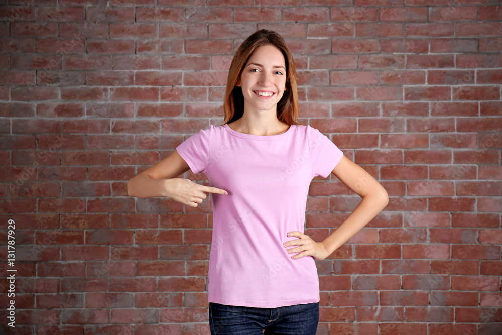 Young woman in blank color t-shirt standing against brick wall Young woman in blank color t-shirt standing against brick wall