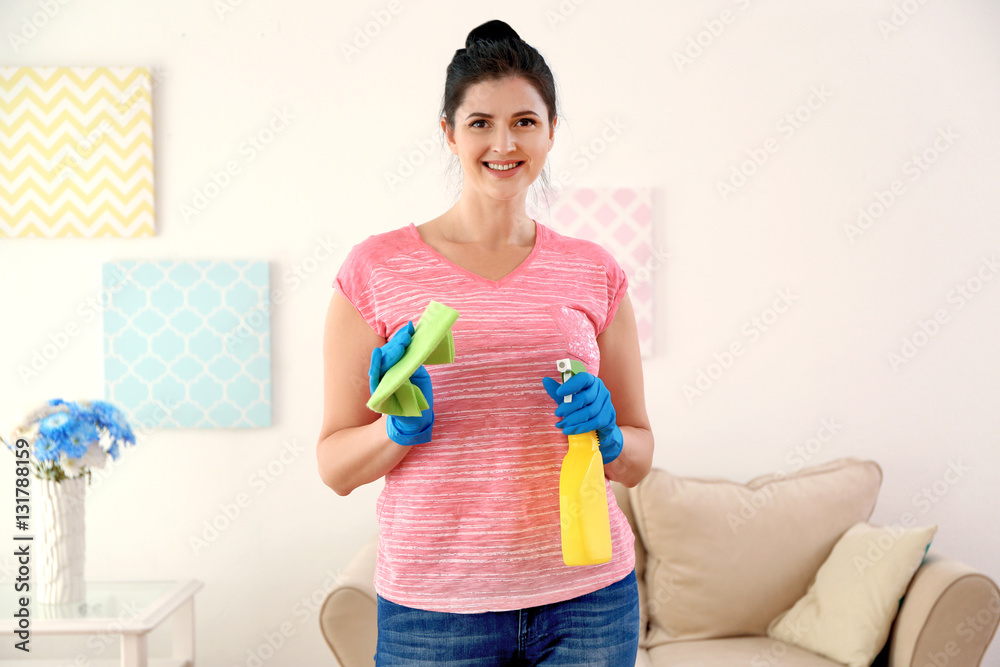 Young cleaner with spray and duster in room Young cleaner with spray and duster in room