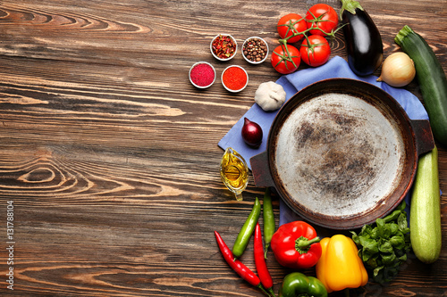 Iron frying pan with products on wooden background