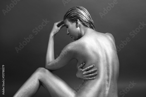 Beautiful woman painted with silver paint on dark background
