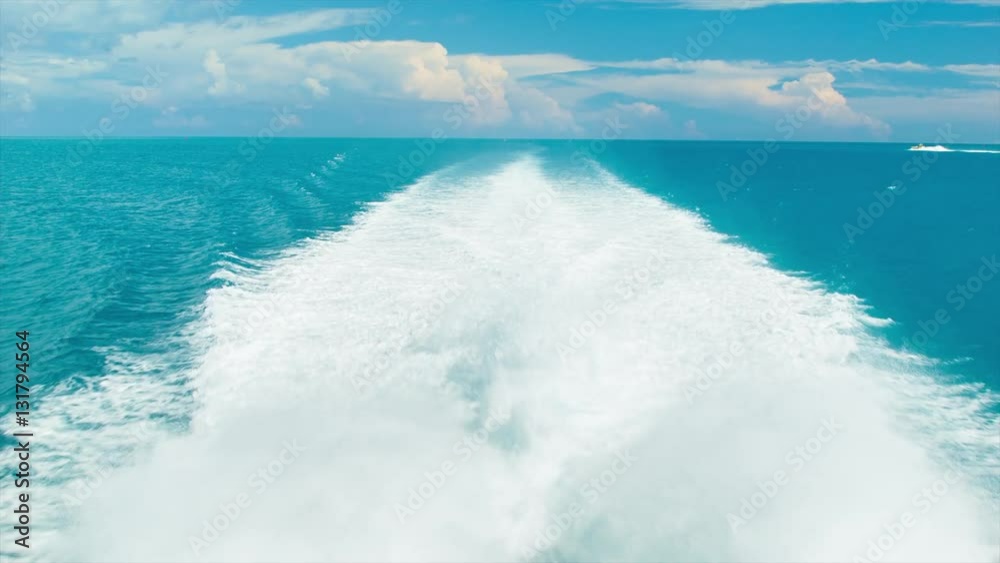White Wake of a Fast Ferry Speeding Through Tropical Water with Bermuda Flag Flapping in the Wind with a View of the Horizon on a Sunny Day