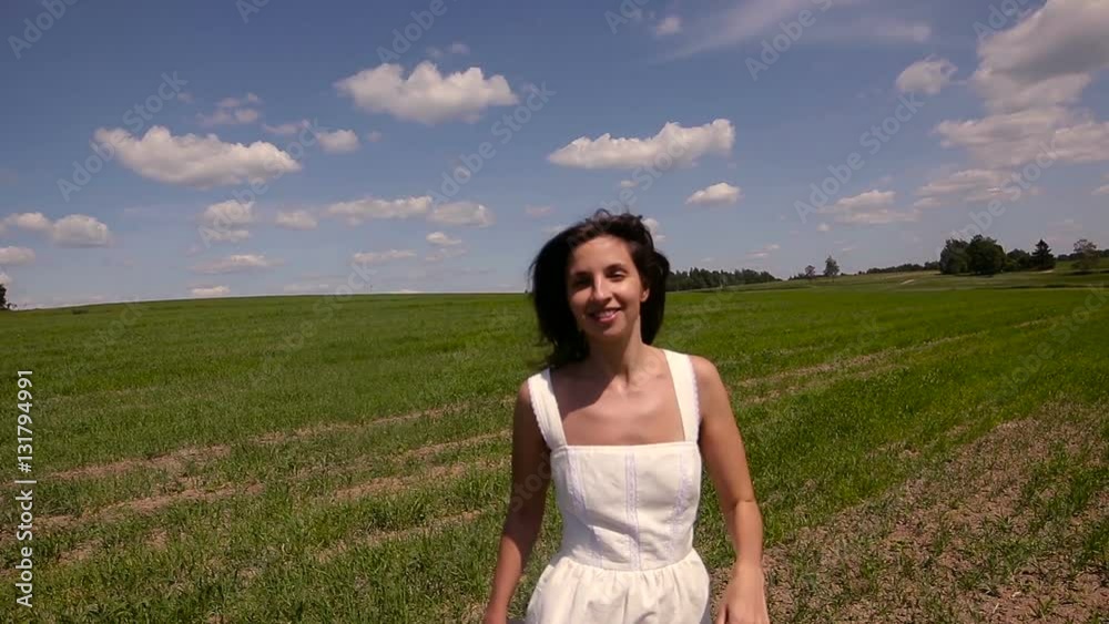 young girl in white dress and clothes straw hat is on the green field with grass and smiles, holds the hand hat, summer young girl in white dress and clothes straw hat is on the green field with grass and smiles, holds the hand hat, summer