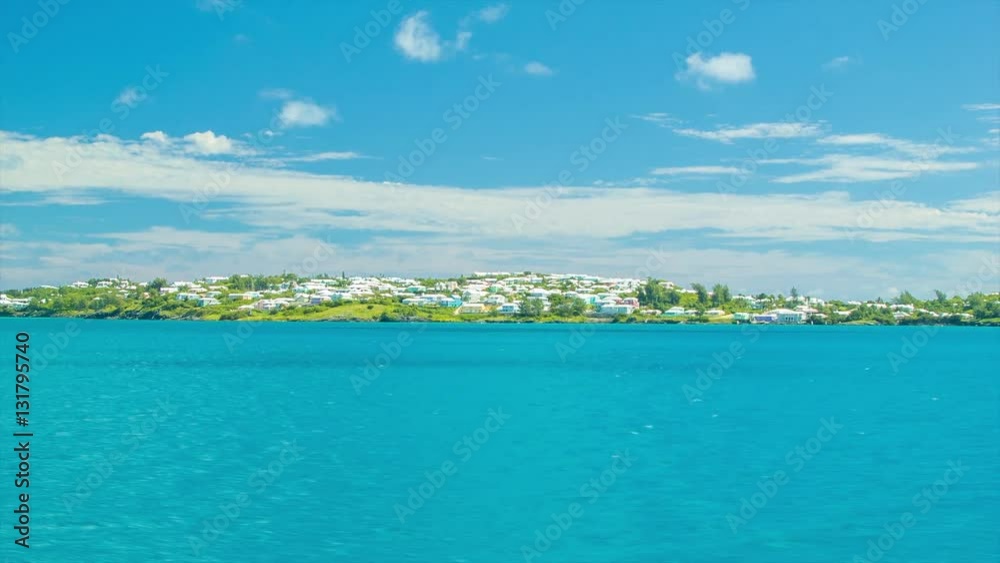 Sailing Past a Tropical Island in Bermuda, Featuring Turquoise Water and a Lush Green Island with Bermudian Architecture on a Sunny Day with White Clouds in a Blue Sky Sailing Past a Tropical Island in Bermuda, Featuring Turquoise Water and a Lush Green Island with Bermudian Architecture on a Sunny Day with White Clouds in a Blue Sky