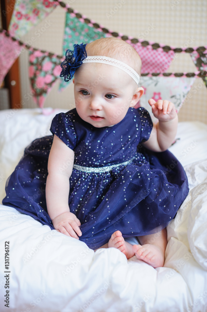 little girl in blue dress sits on the bed little girl in blue dress sits on the bed