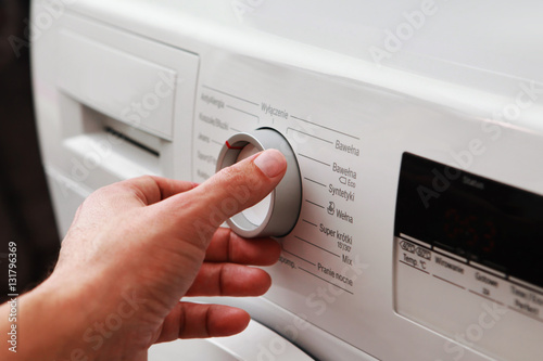 man's hand adjusting washing machine