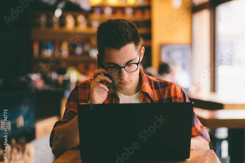 Happy casual man using smartphone and laptop computer