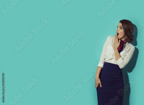Konstfotografi Young suprised woman looking left with her hand beside mouth