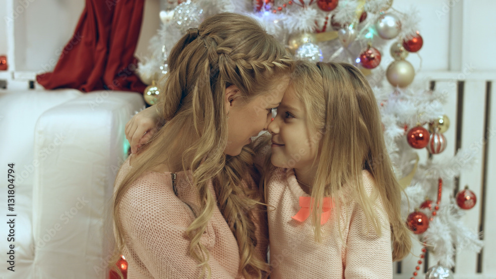 Happy mother and daughter near the a Christmas tree