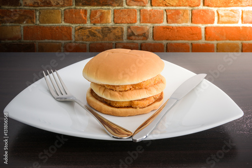 chicken hamburger in white plate with knife and fork, on top tab photo