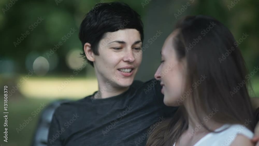 Close-up: two lesbians kisses on bench in park Close-up: two lesbians kisses on bench in park