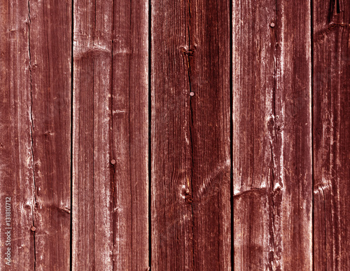 Weathered red wooden fence texture with nails.